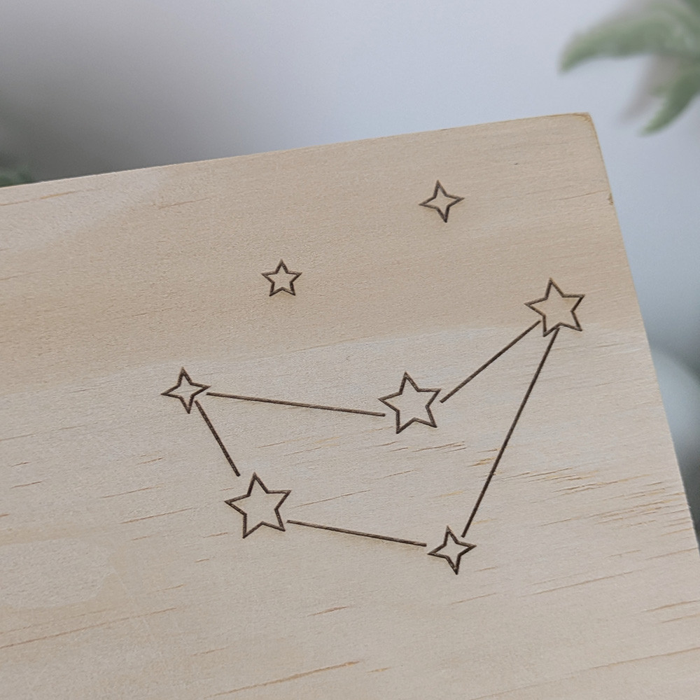 Zoom sur le tracé de la constellation d'étoiles gravée sur le couvercle en bois